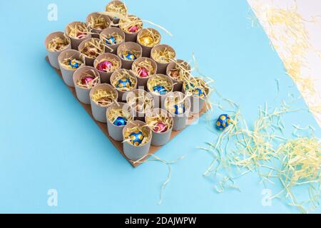 Processo di fare carta igienica rotolo advent calendario mestiere, fai da te, fase 3, riempimento con dolci, vista dall'alto, sfondo blu, attività per bambini tutorial Foto Stock