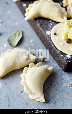 Gnocchi di patate con erbe su uno sfondo blu. Varenyky, vareniki, pierogi, pyrohy - gnocchi con riempimento. Foto Stock