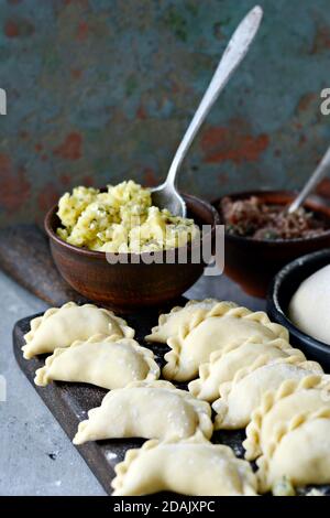 Gnocchi di patate con erbe su uno sfondo blu. Varenyky, vareniki, pierogi, pyrohy - gnocchi con riempimento. Foto Stock