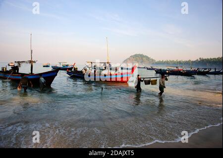 I pescatori birmani portano i loro nigfhts prendere a terra come il sole Sorge sulla spiaggia di Ngapali Myanmar Foto Stock