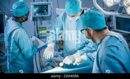 Un team diversificato di chirurgo, assistenti e infermieri professionisti che eseguono interventi di chirurgia invasiva su un paziente nella sala operatoria dell'ospedale. Uso del chirurgo Foto Stock