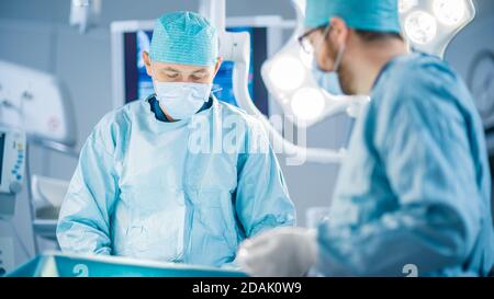 Ripresa in sala operatoria, l'assistente consegna gli strumenti ai chirurghi durante il funzionamento. I chirurghi eseguono l'operazione. Medici professionisti Foto Stock