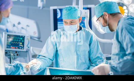 Ripresa in sala operatoria, l'assistente consegna gli strumenti ai chirurghi durante il funzionamento. I chirurghi eseguono l'operazione. Medici professionisti Foto Stock