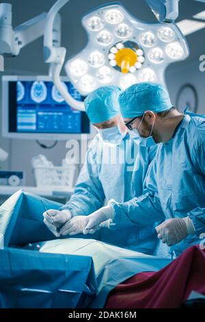 Ritratto dei chirurghi professionisti che eseguono interventi di chirurgia invasiva su un paziente nella sala operatoria dell'ospedale. In background Ospedale moderno Foto Stock