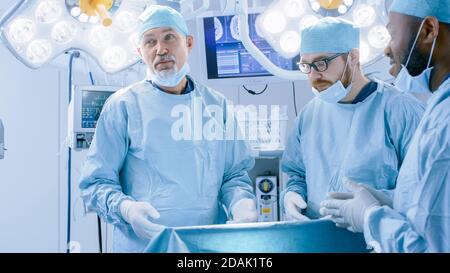 Un team diversificato di chirurgo, assistenti e infermieri professionisti che eseguono interventi di chirurgia invasiva su un paziente nella sala operatoria dell'ospedale. I chirurghi lo hanno Foto Stock