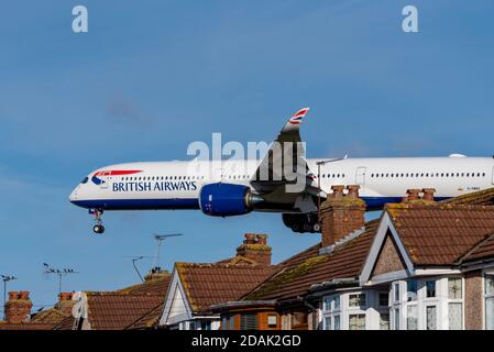 British Airways aereo jet in avvicinamento per atterrare all'aeroporto di Londra Heathrow, Regno Unito, sui tetti delle case vicino all'aeroporto. Proprietà in flightpath Foto Stock