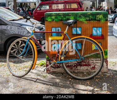 Urban Color - una bicicletta colorata parcheggiata contro un dipinto Cassetta di servizio in una strada cittadina - colore coordinato Foto Stock