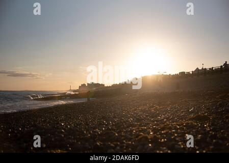 Bagliore dorato del tramonto su costa di spiaggia di ciottoli e oceano calmo Foto Stock