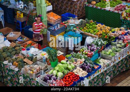 Una signora al suo stand di frutta e verdura locale e tropicale nel mercato a Papeete, Tahiti, Polinesia francese Foto Stock