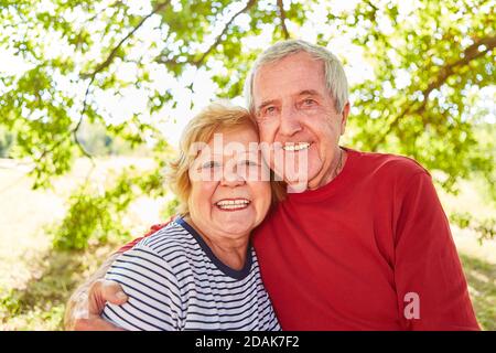 Felice coppia senior in amore braccio in piedi dentro il parco in estate Foto Stock