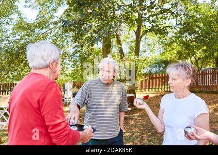 Gruppo di anziani come una squadra che gioca insieme boules in il giardino d'estate Foto Stock