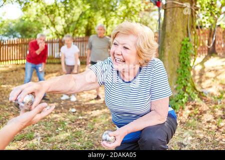 Donna anziana felice che gioca con gli amici in giardino in estate e vincendo Foto Stock