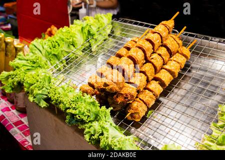 Spiedini di pollo fritti Jock a punta decorati con verdure messe su vassoio. Cibo di strada tailandese facile e conveniente. Selezionare la messa a fuoco. Foto Stock