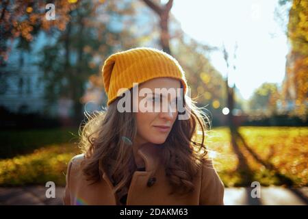 Ciao autunno. Elegante donna di 40 anni in camice beige e cappello arancione fuori sulla strada della città in autunno. Foto Stock