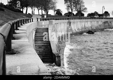 La passerella inferiore lungo il muro del mare presso la riserva costiera di Lynn è allagata da onde che si infrangono. La scena è stata fotografata durante una marea solitamente alta AN Foto Stock