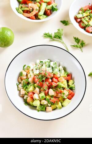 Insalata di avocado, gamberi, pomodoro e mozzarella con verdure in ciotola su fondo di pietra chiaro. Concetto di alimentazione sana. Foto Stock