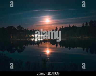 Si illumina di luna su un lago con un castello. Notte mistico scenario. Luna piena su stagno foggy. GATCHINA. Russia. Foto Stock