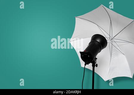 flash stroboscopico di studio fotografico con ombrello bianco su supporto su sfondo ciano. attrezzatura di illuminazione. spazio di copia Foto Stock