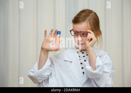 La bambina in un fumetto del medico esamina le provette con i test. Gioco medico educativo. Foto Stock