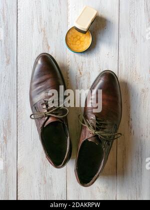Cera protettiva per scarpe in pelle. Concetto di cura delle scarpe. Un paio di stivali classici sul pavimento in legno. Foto Stock