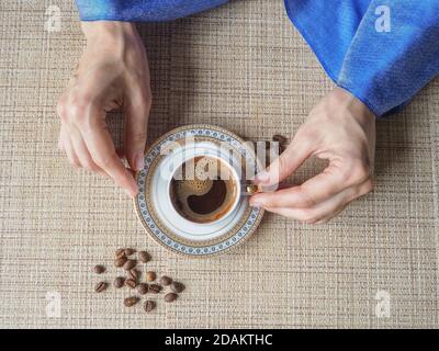 Tenere una tazza di caffè con la mano. La mano contiene un'elegante tazza di caffè. Foto Stock