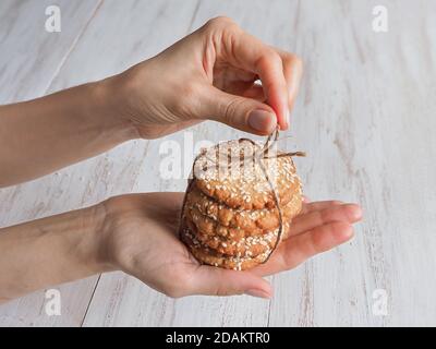 Mani che tengono una pila di biscotti di sesamo freschi. Foto Stock