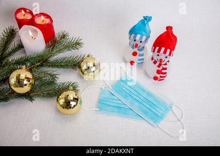Innevati decorativi per il nuovo anno, candele, ramo di abete, maschera medica. Concept, Natale nell'epidemia di coronavirus, congratularsi con gli amici, ma rimanere in corantin. Foto di alta qualità Foto Stock
