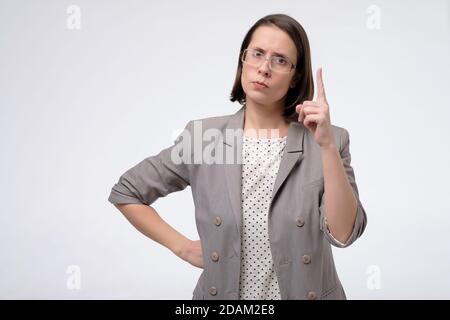 Donna di affari matura di mezza età che punta con il dito in su che dà consigli Foto Stock