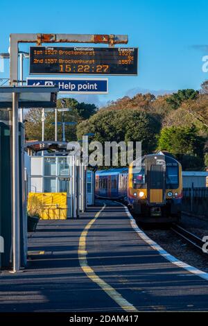 un treno che si avvicina alla stazione del molo di lymington e la piattaforma nella nuova foresta per incontrare l'isola del traghetto wight. Foto Stock