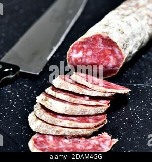 Fette di salame artigianale italiano Felino su un tagliere da cucina. Felino, Parma, Emilia Romagna / Italia Foto Stock