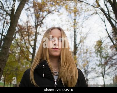 Ampio Ritratto ad angolo basso di una bella giovane bionda donna Nel Parco Autunno Foto Stock