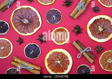 Stecche di cannella, anice stellato e arance secche e limoni vista dall'alto. Modello di spezie per il VIN brulé. Briciole secche di arancia, cannella e anice su una schiena rossa Foto Stock