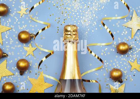 Tema natalizio con una bottiglia di champagne. Bottiglia di champagne e decorazioni natalizie. Palline d'oro, stelle e vista dall'alto del nastro. Composizione del nuovo anno Foto Stock