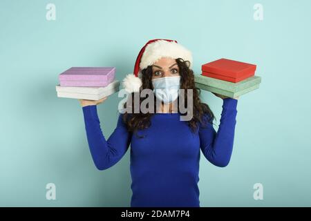 Ragazza felice con maschera facciale riceve regali di Natale. Sfondo ciano Foto Stock