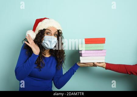 Ragazza felice con maschera facciale riceve regali di Natale. Sfondo ciano Foto Stock