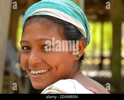 Giovane bella indiana Mishing tribale donna da Majuli Island guarda sopra la sua spalla e sorride per la macchina fotografica. Foto Stock