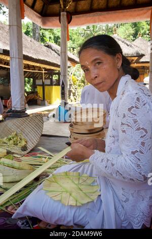 Donna balinese che lapida piccoli cesti per offerte religiose al complesso del tempio Gunung Kawi, Tampaksiring, Bali, Indonesia Foto Stock