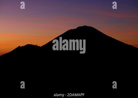 Vista all'alba dal bordo della caldera del Monte Batur verso il Monte Agung e il Monte Abang. Bali, Indonesia Foto Stock