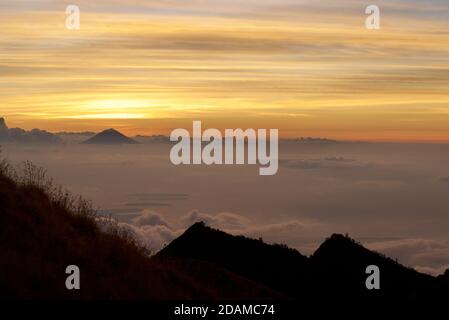 Monte Agung su Bali visto dal bordo del cratere del vulcano Rinjani, Lombok, Indonesia. Dawn Foto Stock