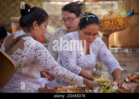 Donne balinesi in abiti tradizionali che preparano offerte di templi, tempio Sakenan, Bali, Indonesia Foto Stock