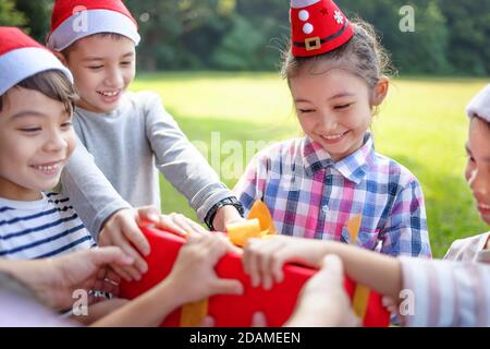 Felici i bambini nel cappello rosso di Santa e che tengono i regali di Natale Foto Stock