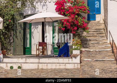 Ombrellone e fiori rossi di fronte alla casa bianca A Cadaques Foto Stock