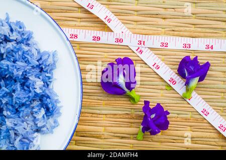 Riso Blue Sticky fatto da Butterfly Pea flower (ali di maiale asiatiche) con nastro di misurazione. Buono per salute. copyspace. Concetto di dieta Foto Stock