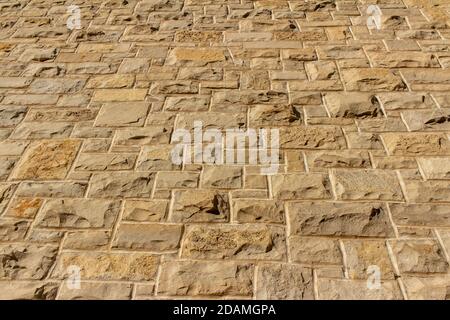 Struttura completa verso l'alto sfondo di una moderna parete in pietra naturale marrone beige con struttura in muratura in ashlar, con blocchi di pietra calcarea taglio ruvido Foto Stock