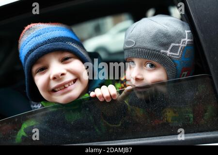 I ragazzi guardano fuori dal finestrino dell'auto in autunno Foto Stock