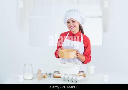 ragazza setaccia la farina attraverso un setaccio, cucina. Foto Stock