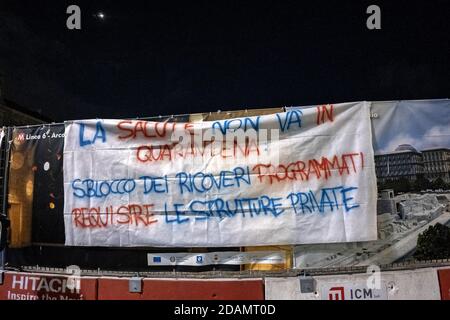 Covid 19 - il fallimento di un sistema di Napoli.dimostrazione unitaria di diversi movimenti in Piazza Plebiscito, presieduta da un imponente esercito di forze dell'ordine. «per il sostegno sanitario ed economico di ogni ricchezza ai ricchi». Questo è lo striscione esposto da circa cento manifestanti di fronte all'ingresso della Prefettura di Napoli, in Piazza Plebiscito. I dimostranti hanno acceso un po' di fumo rosso. Un'altra bandiera reca l'iscrizione «No alla chiusura dell'ospedale di San Gennaro». L'ingresso al Palazzo del Governo e' sorvegliato dalla polizia in equipaggiamento da sommossa. (Foto di Alessandro Barone/Pacific Foto Stock