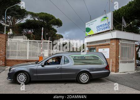 L'automobile funeraria trasporta una bara fuori dell'ospedale. Si dice che gli ospedali in Italia si trovino di fronte a un punto di rottura mentre lottano per stare al passo con la v Foto Stock