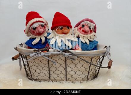 Tre gnomi colorati a crocheted fatti in cestino con bianco sfondo Foto Stock