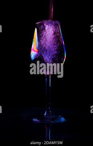 Vino versato in una tazza di bicchiere in fondo nero Foto Stock